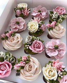 cupcakes decorated with pink and white flowers in a box