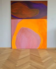 an abstract painting on the wall in front of a chevron wooden floor and chair