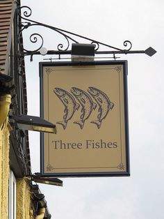 a sign for three fishes hanging from the side of a building