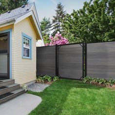 a house with a fence in front of it and some flowers on the side yard