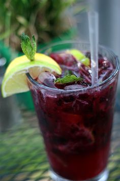 a close up of a drink in a glass on a table with lemon wedges