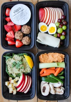 four plastic trays filled with different types of fruits and veggies on top of a wooden table