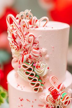 a three tiered cake with candy canes on top and candies all over it