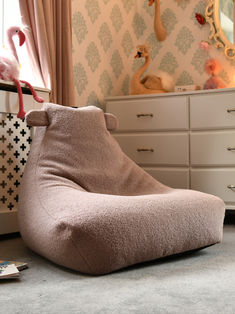 a bean bag chair sitting on the floor in front of a dresser with flamingos