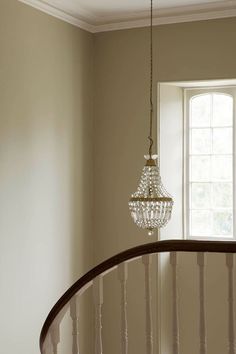 a chandelier hanging from the side of a stair case next to a window