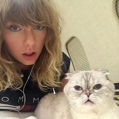 a woman holding a white cat in her arms and looking at the camera with an amazed look on her face