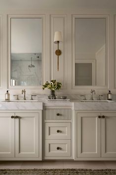 a bathroom with two sinks and mirrors on the wall next to each other in white cabinets