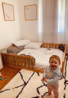 a small child standing in front of a bed