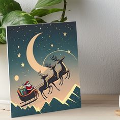 a santa claus sleigh flying through the night sky with his reindeer art board print