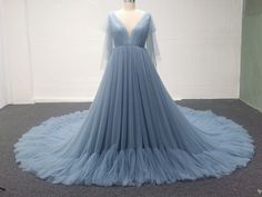 a dress on display in a room with white walls and grey carpeting, it has a light blue tulle skirt