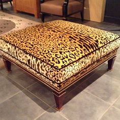 a leopard print ottoman sitting on top of a tile floor next to chairs and tables