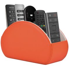 there are four remotes in the holder on this white background and one is orange