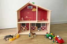 a toy farm house with horses and cows in the yard next to it on top of a hard wood floor