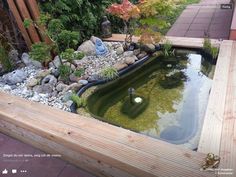 a small pond in the middle of a garden with rocks and gravel around it, surrounded by wood planks