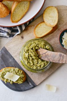 bread and pesto spread in small bowls on a cutting board next to garlic bread