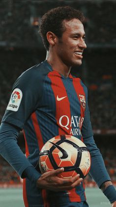 a young man holding a soccer ball in his right hand and smiling at the camera