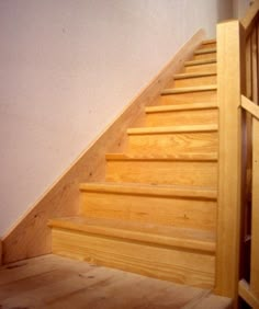 a wooden stair case next to a white wall