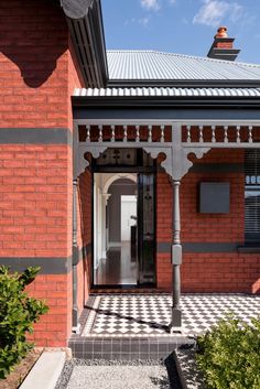 a red brick house with a black and white checkered walkway leading to the front door