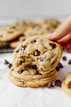 a hand picking up a chocolate chip cookie