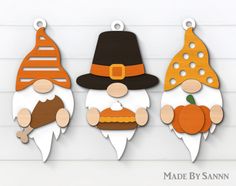 three wooden cutouts of gnomes with hats and pumpkins