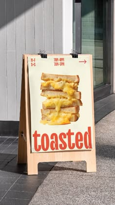 a sign that is on the sidewalk advertising toasted breads and cheese slices in front of a building