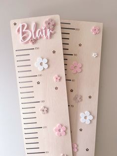 two wooden rulers with flowers and the word blai written on them are hanging on a wall