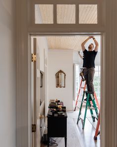 a man on a ladder painting the ceiling