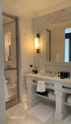 a bathroom with marble walls and flooring, white counter tops and two sinks in front of a large mirror