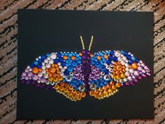 a colorful butterfly made out of buttons on a black background