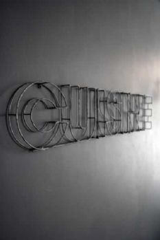 a metal sign on the wall that says cursive