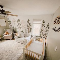 a baby's room decorated in white and gold with trees on the wall behind it