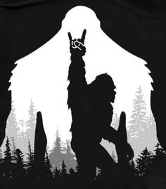 the silhouette of a person holding an animal in front of a mountain with trees on it