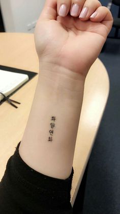 a woman's wrist tattoo with chinese writing on the left side of her arm