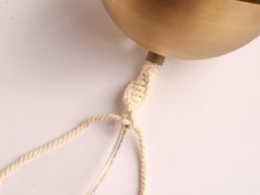 a white rope is attached to a brass colored light fixture on a white table top