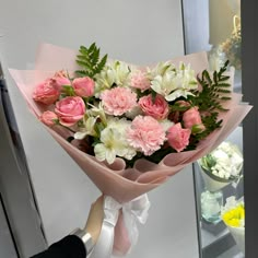 a bouquet of pink and white flowers is being held