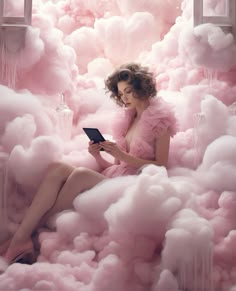 a woman is sitting in a cloud of pink clouds while looking at an electronic device