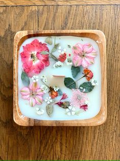 a wooden tray filled with flowers and leaves on top of a wood floor next to a wall