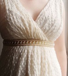 a woman wearing a white dress with a gold belt