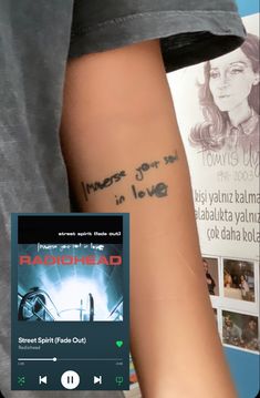 a person with a tattoo on their arm next to a book and an mp3 player