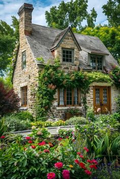 an old stone house surrounded by flowers and greenery