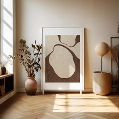 an art print is displayed on the wall next to two vases and a potted plant