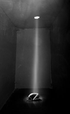 a black and white photo of a light coming from the ceiling in an empty room