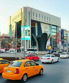 many cars are driving down the street in front of a building with an unusual design