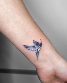 a small blue bird tattoo on the wrist