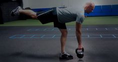 a man doing push ups on a gym floor with a kettle in his hand and one leg bent forward