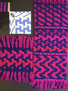 two knitted scarves with different patterns and colors on top of each other next to a piece of paper