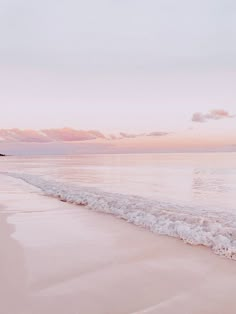 an ocean beach with waves coming in to shore and the sun setting on the horizon