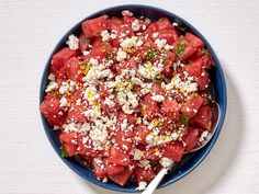 watermelon salad with feta cheese and herbs in a blue bowl on a white surface