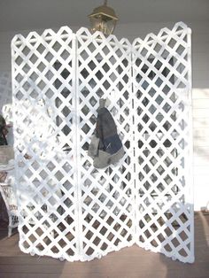 a room divider made out of white plastic lattices with a coat hanging on it