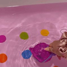 a person in a pink bathtub with polka dots on the floor and a purple bag